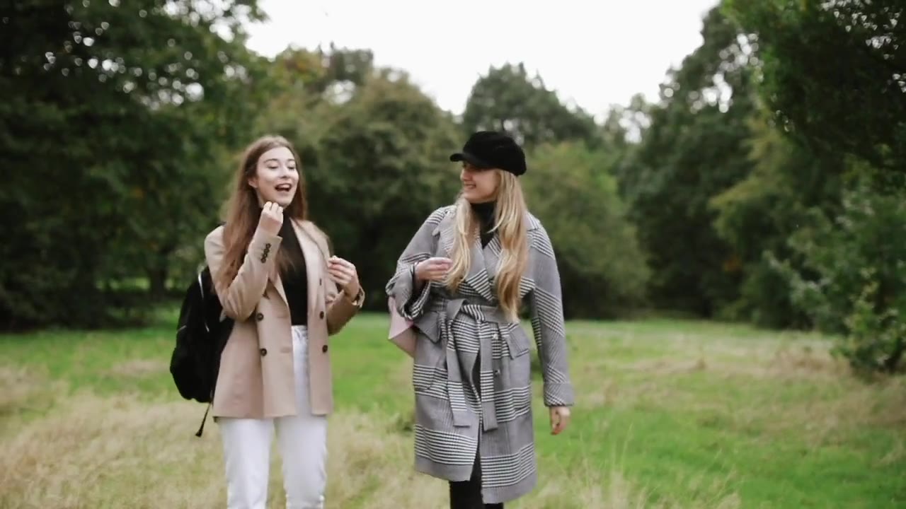 Two women talking while walking in a park.
