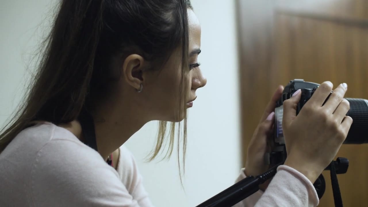 A woman adjusting a camera before filming.